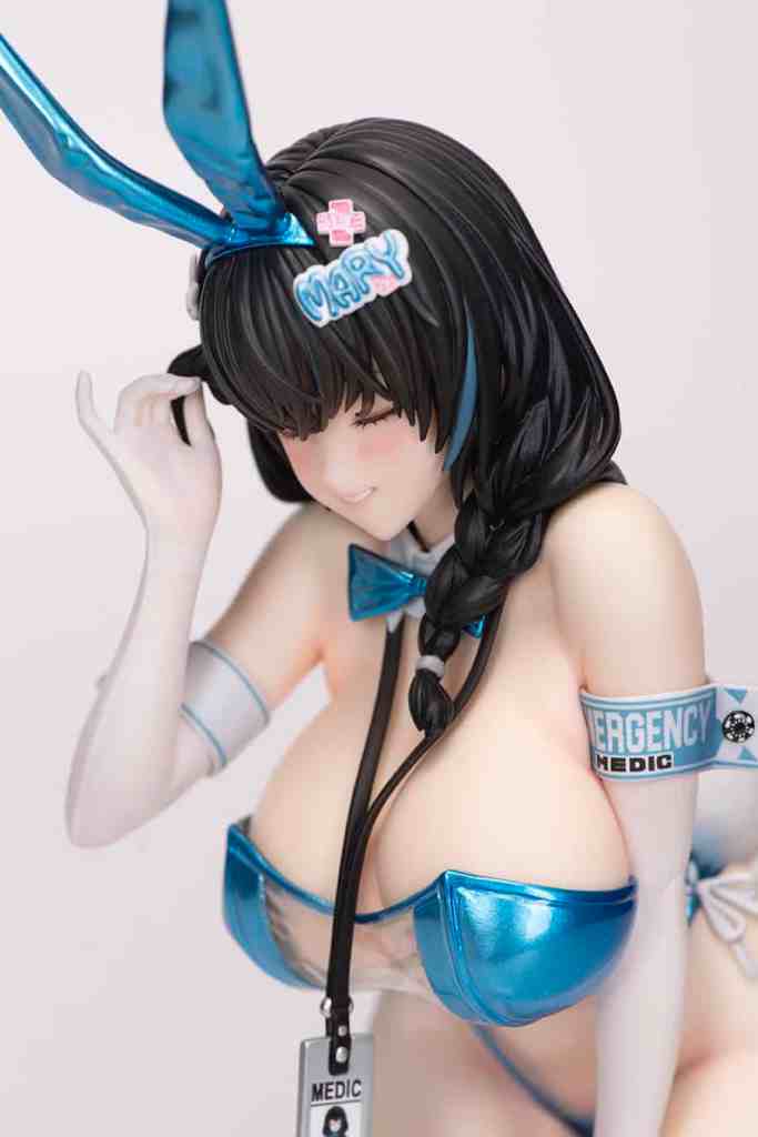 NIKKE メアリーのフィギュア。青いバニー耳と医療装備を身に着けたキャラクター。明るい表情で、片手を髪に添えている。