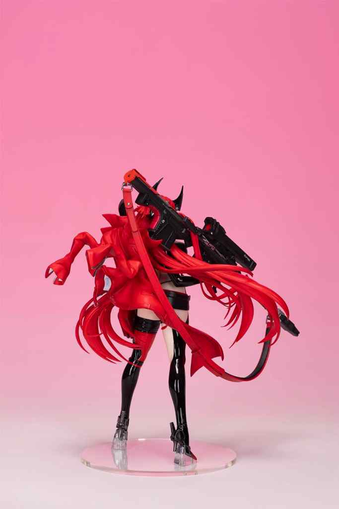 A figure of a character in a red hooded outfit, holding a black weapon, with long red hair and a striking pose against a pink background. The figure includes two face parts and features intricate details.