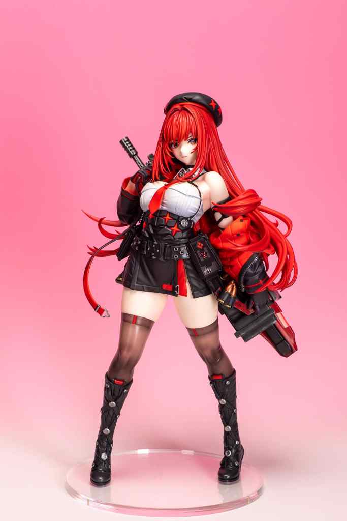 A detailed figure of a character with long red hair, wearing a black and red outfit and holding a weapon, posed against a pink background.