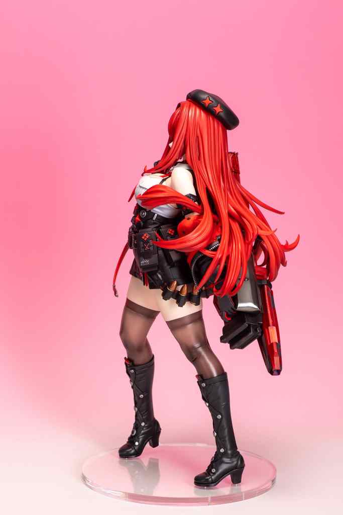 フィギュアの側面を示し、赤い髪と黒い帽子を着用したキャラクター。ピンクの背景に立っており、衣装には武器や装飾が含まれている。