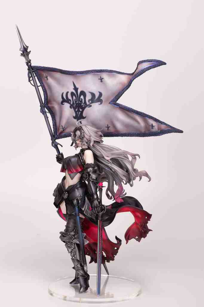 A detailed figure of a female warrior standing confidently, holding a flag with a decorative design, wearing black armor with red accents and long flowing hair.