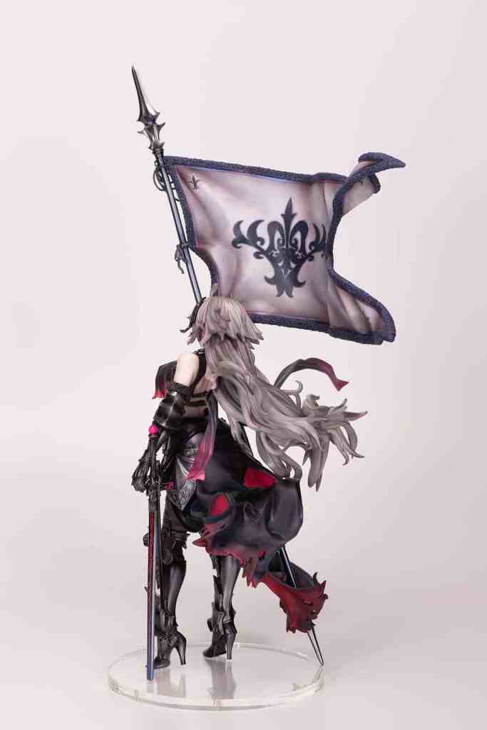 A detailed figurine of a character holding a flag, with long flowing hair and a black outfit, showcasing intricate designs on the flag and costume.