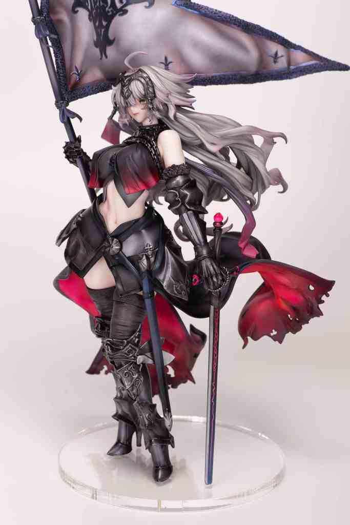 A detailed figurine of a female warrior holding a flag, adorned in dark armor with red accents, featuring long flowing hair and standing on a clear base.