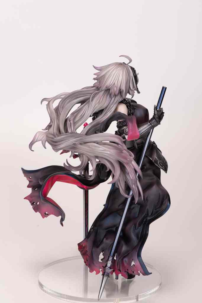 A detailed figure of a character with long, flowing hair and a dark, elegant outfit, holding a spear and standing on a clear base.