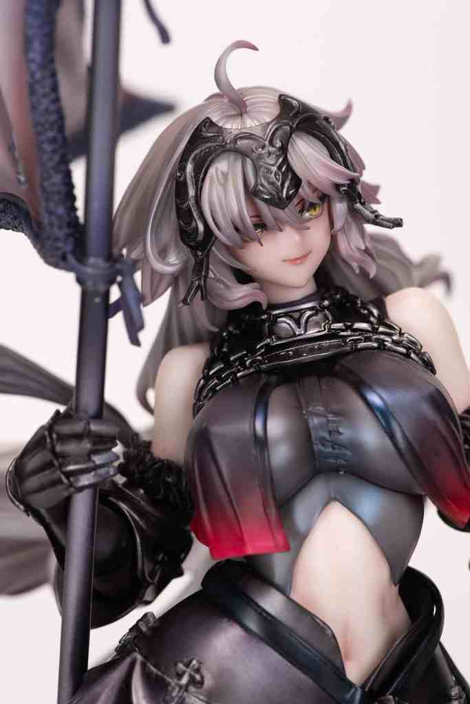 Close-up of a detailed anime-inspired figurine with long hair, wearing dark armor and holding a staff, featuring intricate designs and a fierce expression.