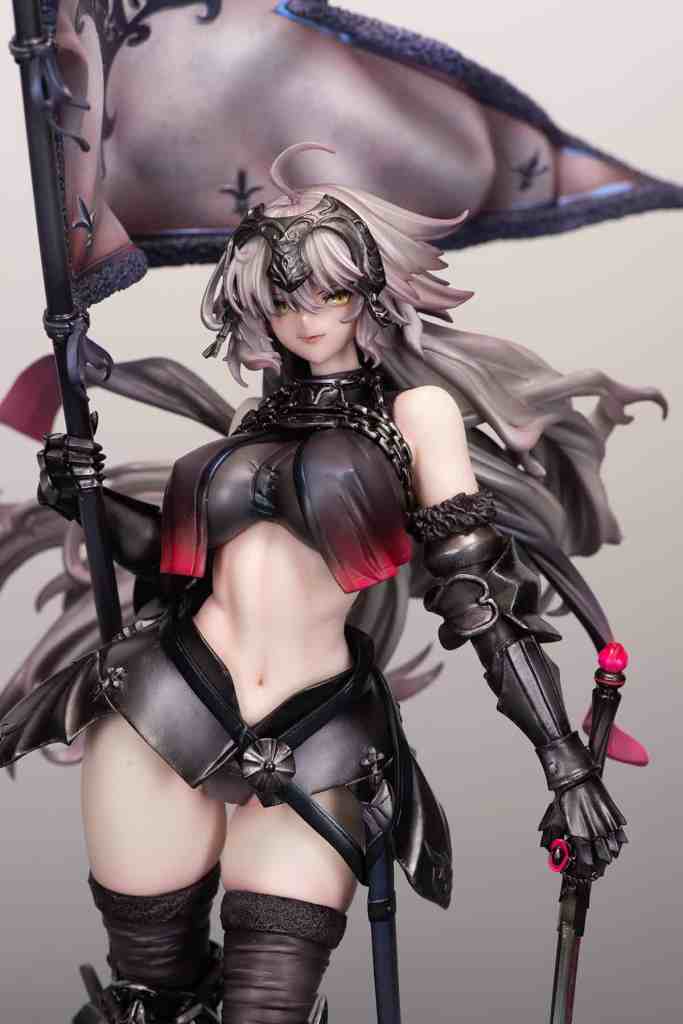A detailed figure of a female character with long hair, wearing a black and red outfit, holding a flag and a staff, with an intricate design and accessories.