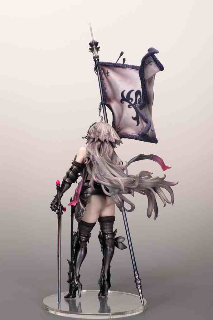 A stylized figurine of a female character holding a flag, viewed from the back. She has long, flowing hair and is wearing a revealing outfit with black boots and a staff.