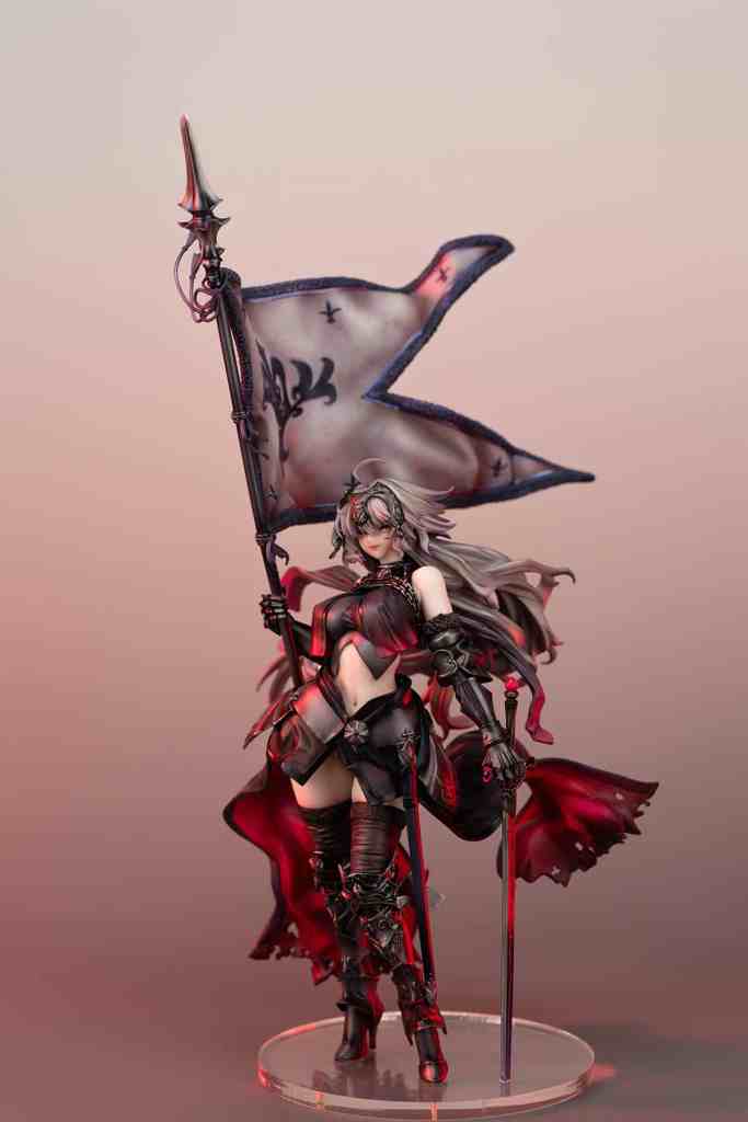 A detailed figurine of a female warrior holding a flag and a spear, dressed in dark armor with a flowing red cape, set against a soft gradient background.