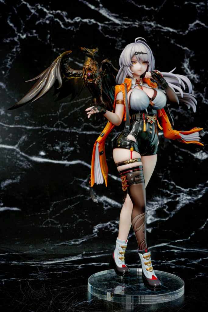 A detailed figure of a character with silver hair and a dark outfit, featuring a striking combination of orange and black elements. She is posed confidently with one hand near her mouth, accompanied by a black winged creature on her shoulder, set against a marble background.