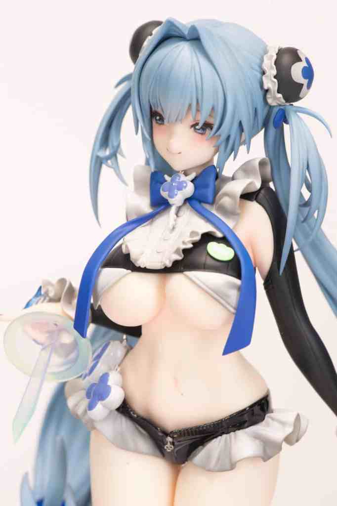 A detailed figurine of a character with blue hair styled in two ponytails, wearing a revealing outfit with black and white elements, alongside a blue bow and flower accessories.