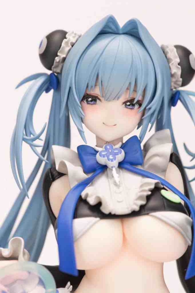 Close-up of a figurine featuring a character with blue hair styled in pigtails, wearing a maid outfit with a large blue bow and a playful expression.